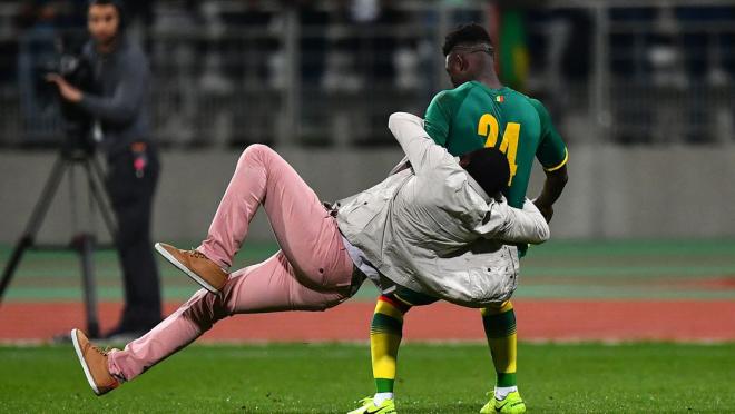 Senegal’s Lamine Gassama is tackled by a fan.